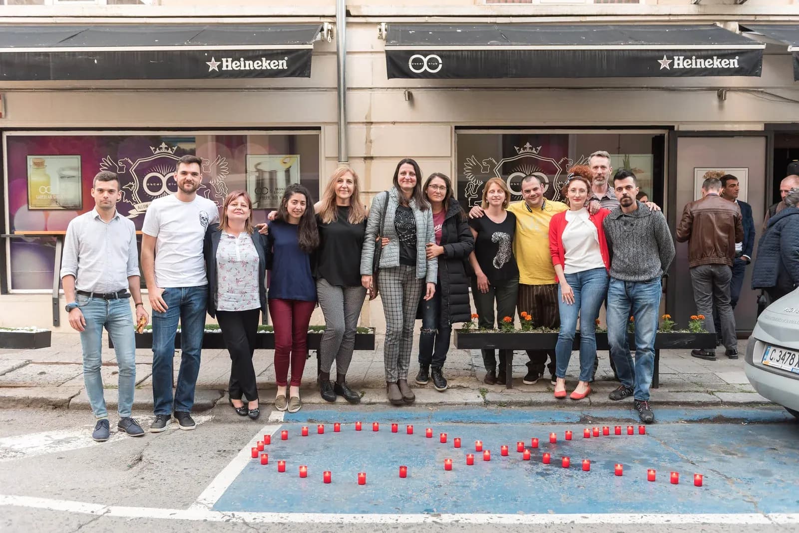 Participantes detrás de un lazo rojo formado con velas