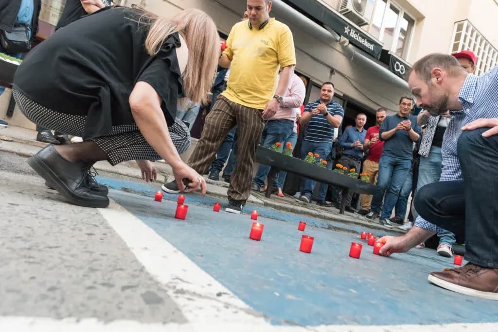 Participantes colocan velas rojas en la acera