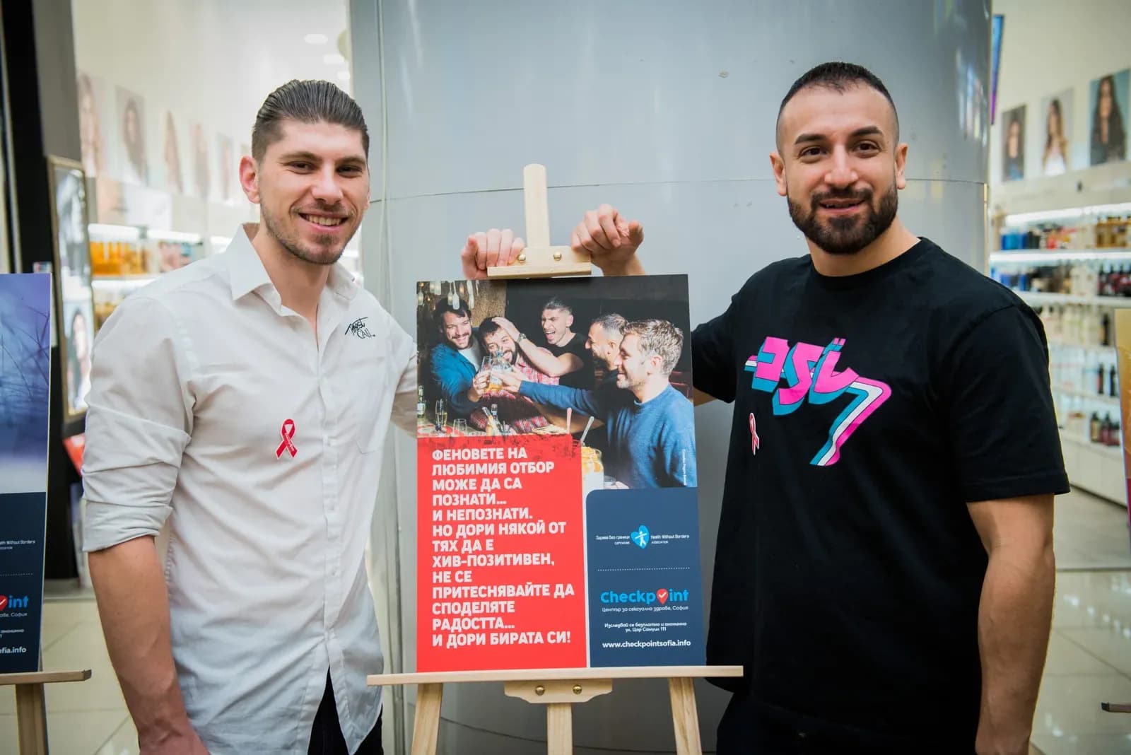 Zwei Teilnehmende neben einem Ausstellungsplakat